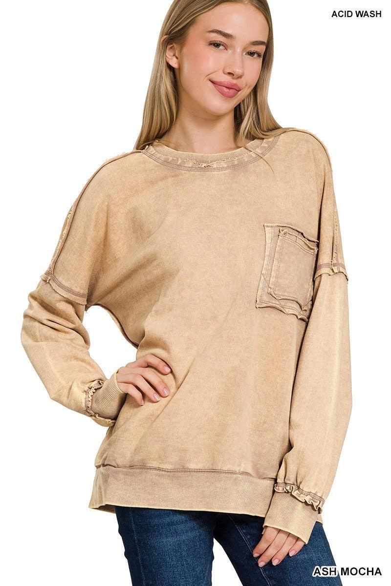 Blonde woman wearing a boyfriend fit drop shoulder sweatshirt pullover, with front pocket accent, exposed raw seams, and all over acid wash detail.