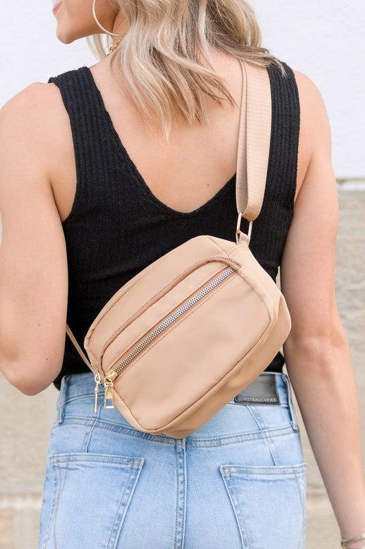 Person wearing a beige crossbody bag with a blurred background