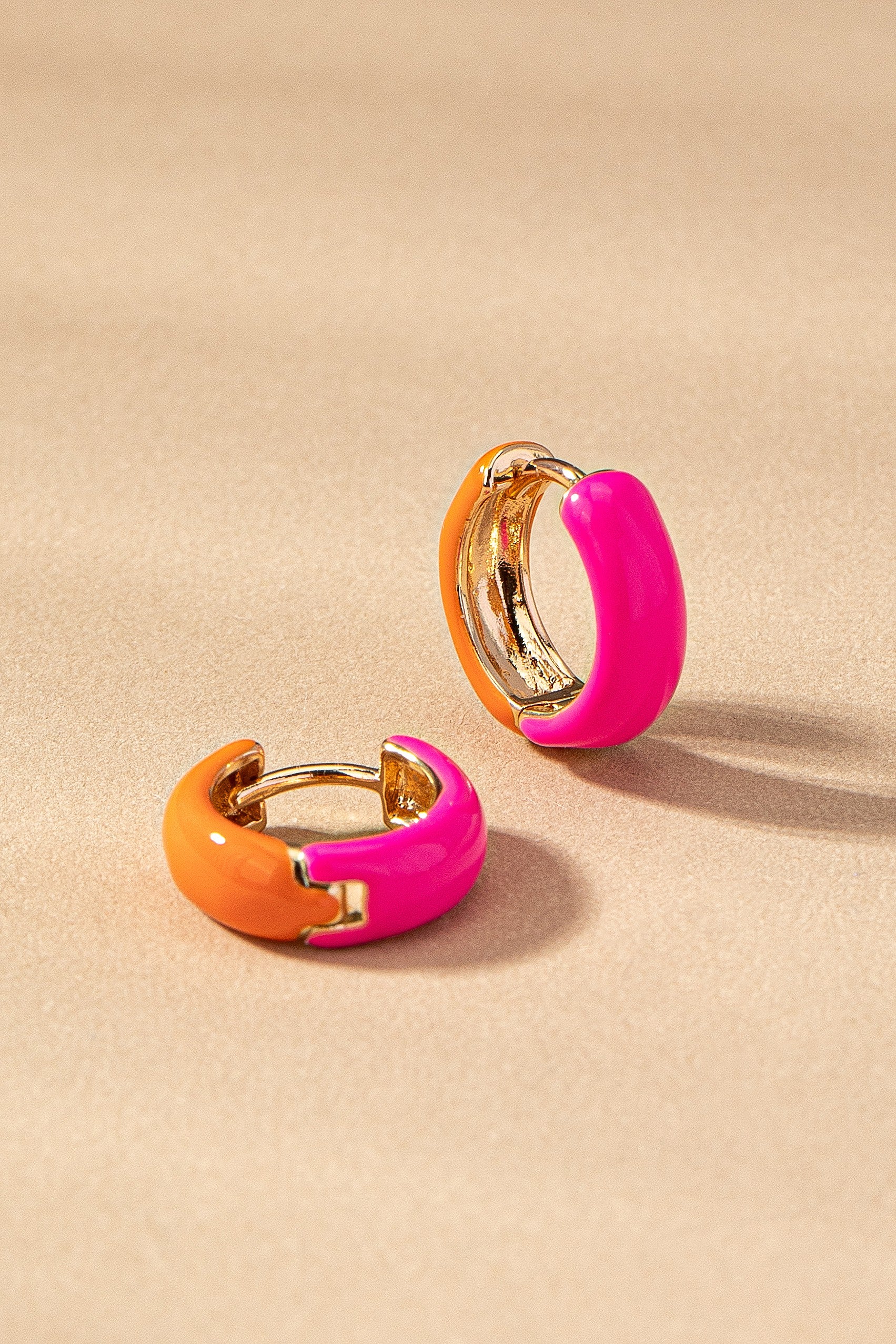 Pair of colorful hoop earrings on a beige background