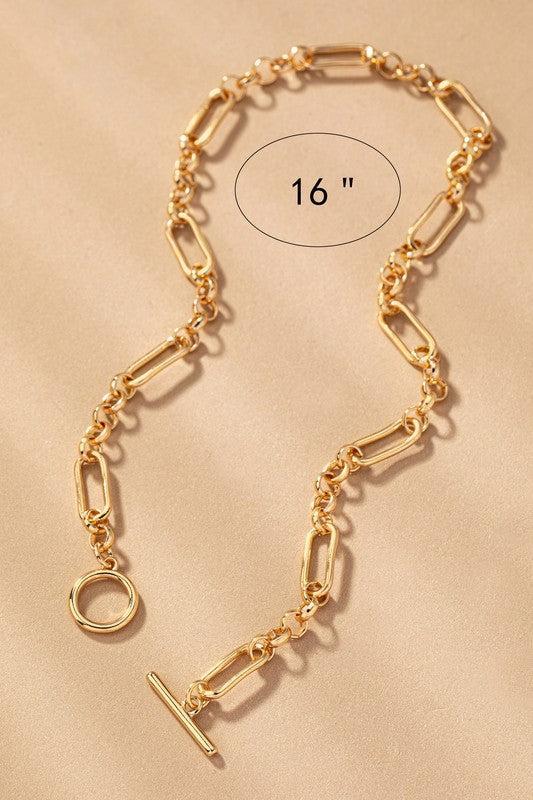 Gold chain necklace on a beige background with a measurement label.