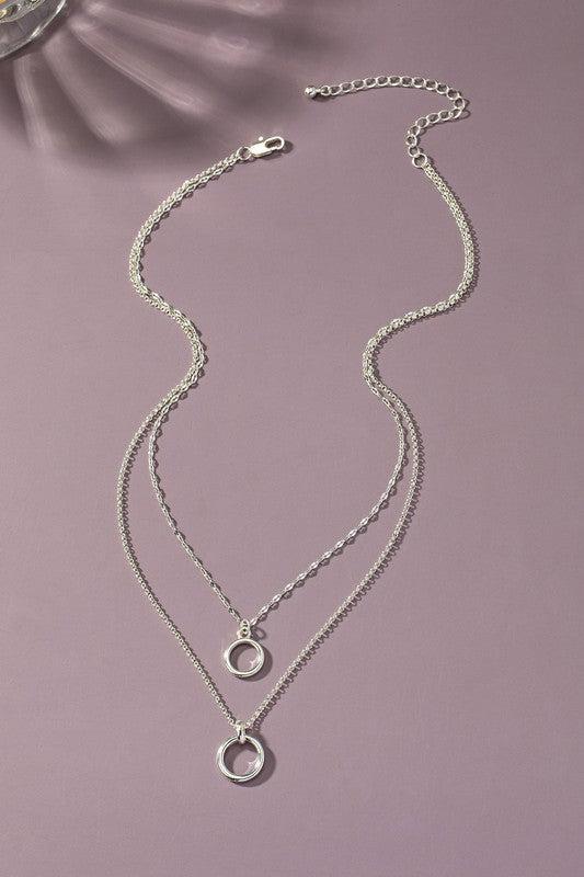 Silver necklace with circular pendants on a purple background