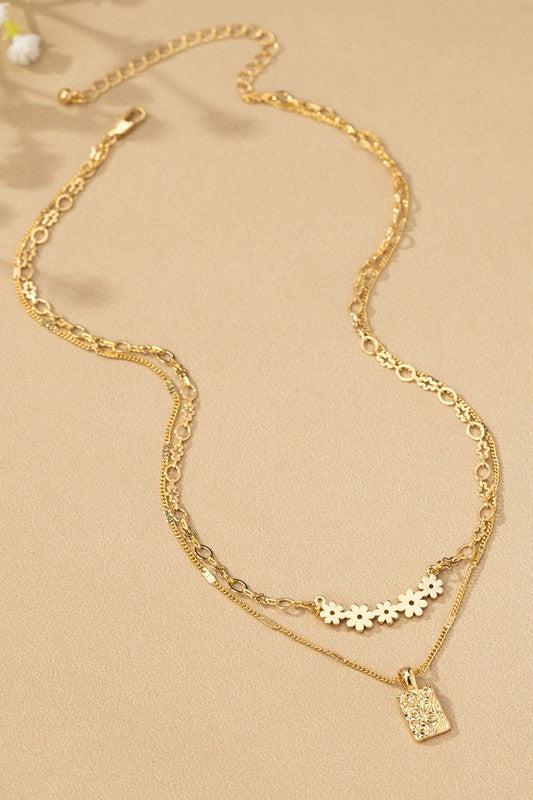 Flat lay of a gold necklace that has two layers with dainty floral details