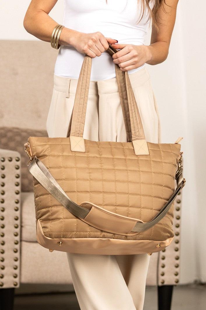 Woman holding a white nylon quilted traveler tote bag.