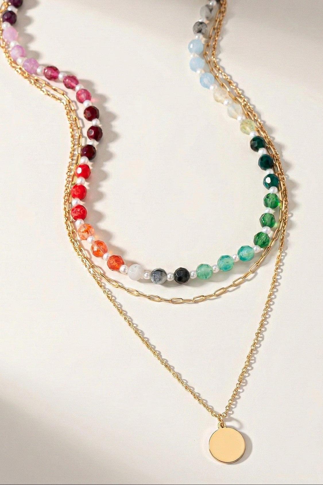Stack of colorful beaded necklaces on a light background