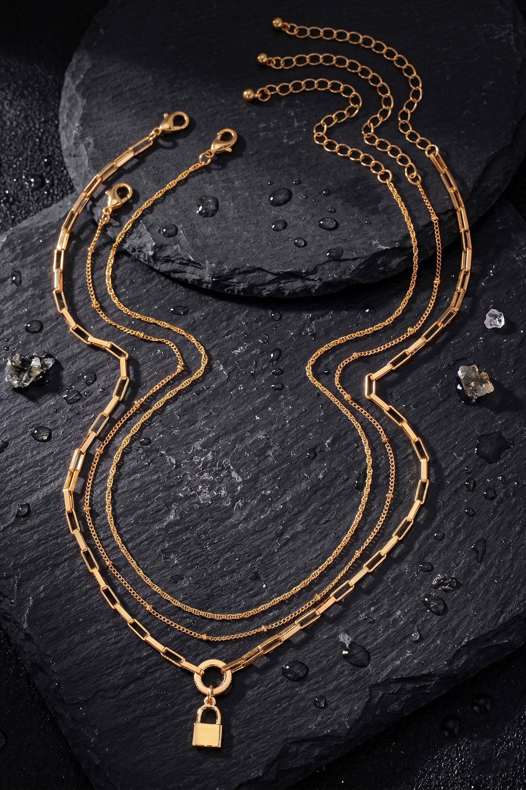 Gold necklaces on a dark stone surface