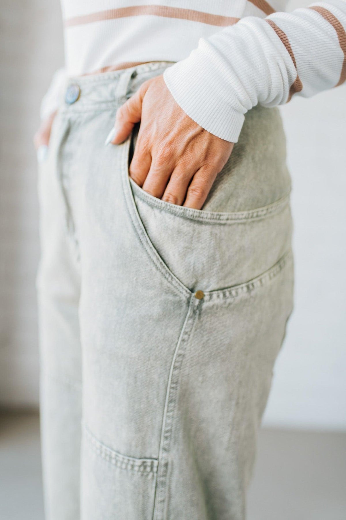 Blonde woman wearing Mineral Washed Mid Rise Barrel Shape Pants with patch detail on leg.