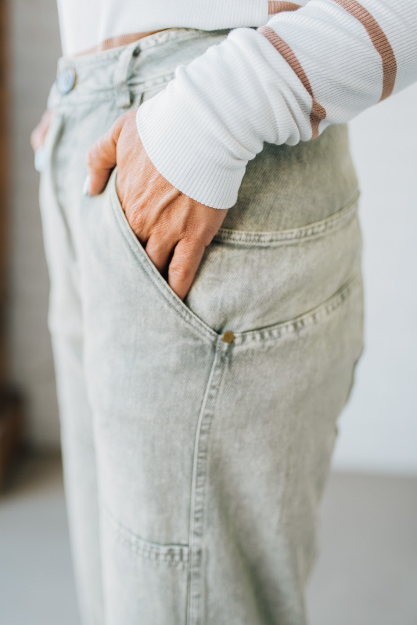 Blonde woman wearing Mineral Washed Mid Rise Barrel Shape Pants with patch detail on leg.