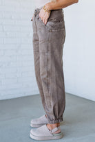 Person wearing brown cargo pants with a white brick wall background