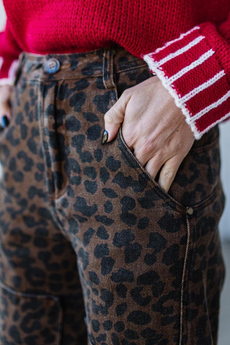 Person wearing a red sweater with striped cuffs and leopard print pants.