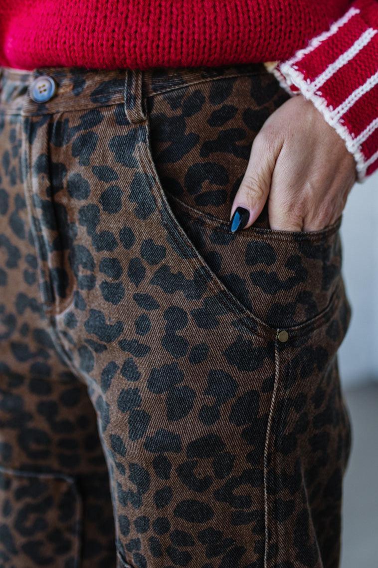 Person wearing leopard print pants with a red and white striped sleeve.