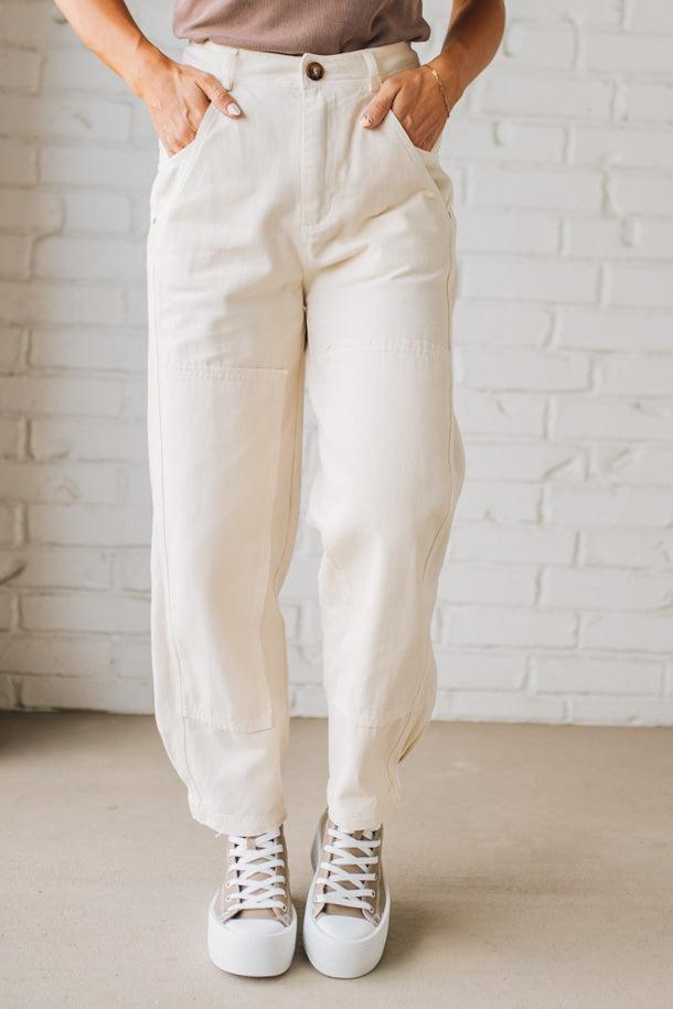 Person wearing white pants and white sneakers against a white brick wall.