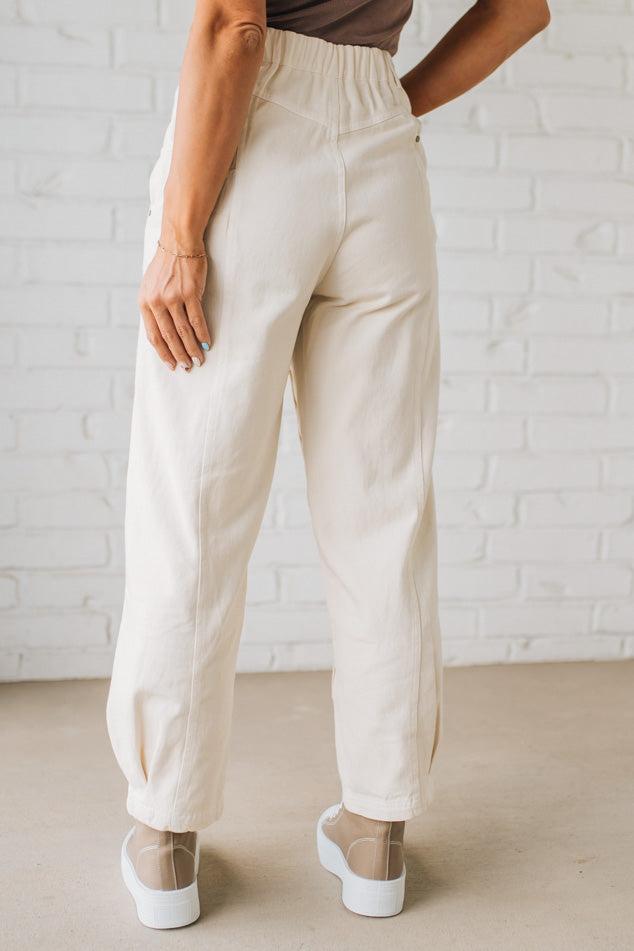 Person wearing white pants against a white brick wall.