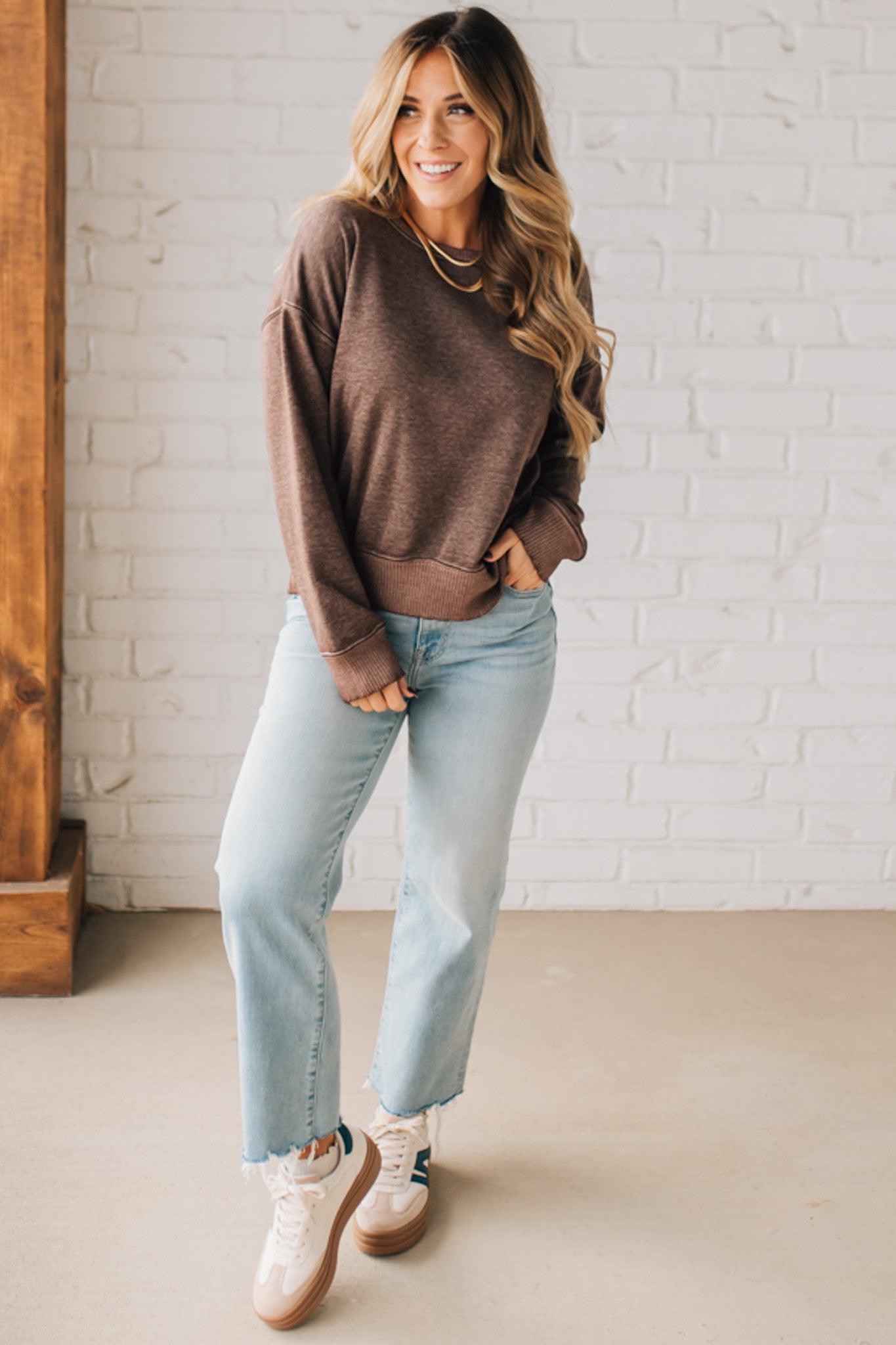 BLONDE WOMAN MODELING A LONG SLEEVE ACID WASHED PULLOVER WITH RIBBED DETAIL ON THE NECKLINE, SLEEVE CUFFS AND HEMLINE