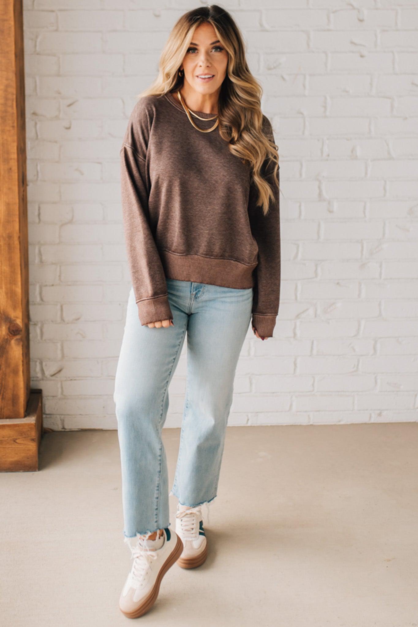 BLONDE WOMAN MODELING A LONG SLEEVE ACID WASHED PULLOVER WITH RIBBED DETAIL ON THE NECKLINE, SLEEVE CUFFS AND HEMLINE