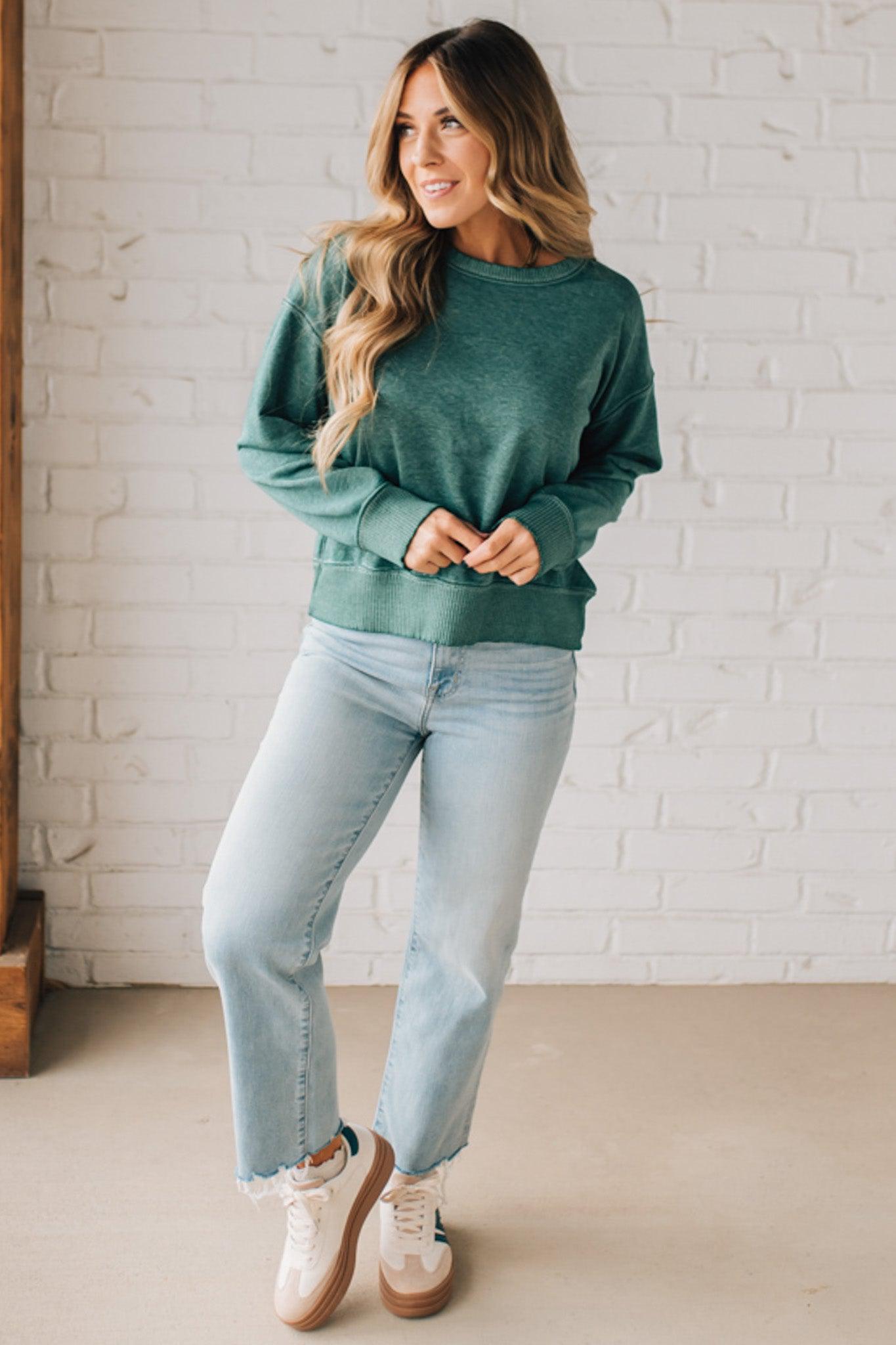BLONDE WOMAN MODELING A LONG SLEEVE ACID WASHED PULLOVER WITH RIBBED DETAIL ON THE NECKLINE, SLEEVE CUFFS AND HEMLINE