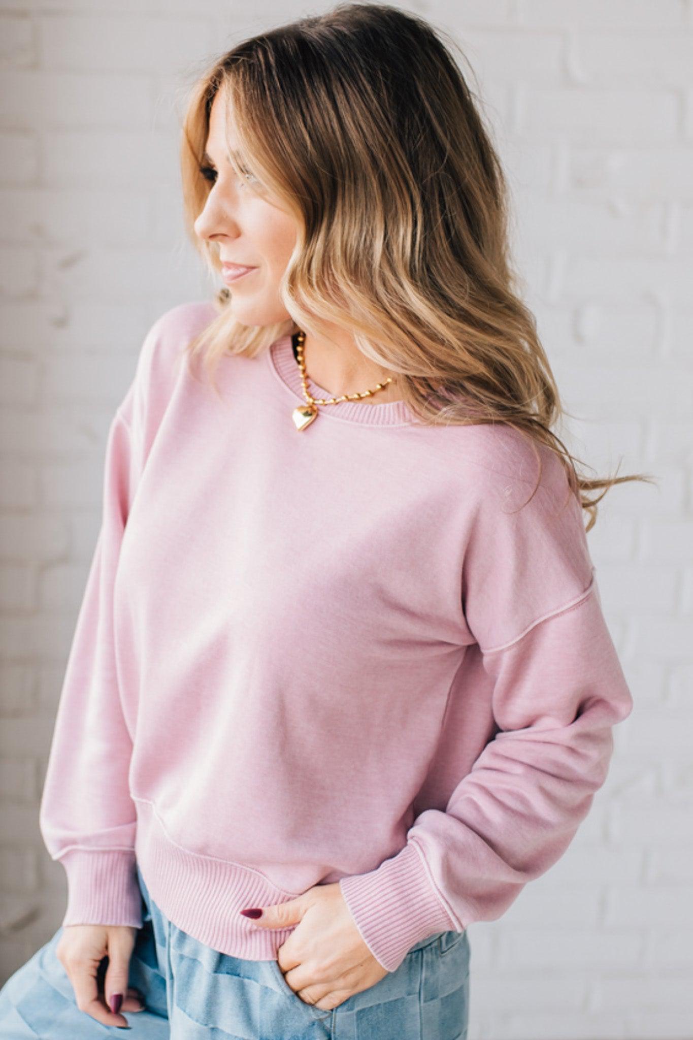 BLONDE WOMAN MODELING A LONG SLEEVE ACID WASHED PULLOVER WITH RIBBED DETAIL ON THE NECKLINE, SLEEVE CUFFS AND HEMLINE