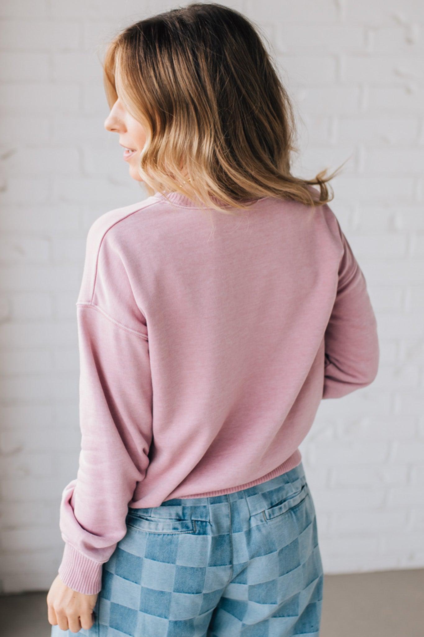 BLONDE WOMAN MODELING A LONG SLEEVE ACID WASHED PULLOVER WITH RIBBED DETAIL ON THE NECKLINE, SLEEVE CUFFS AND HEMLINE