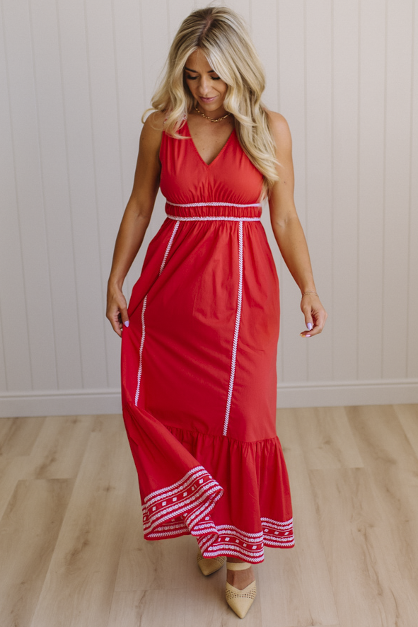 Woman wearing a red dress with white trim on a wooden floor.