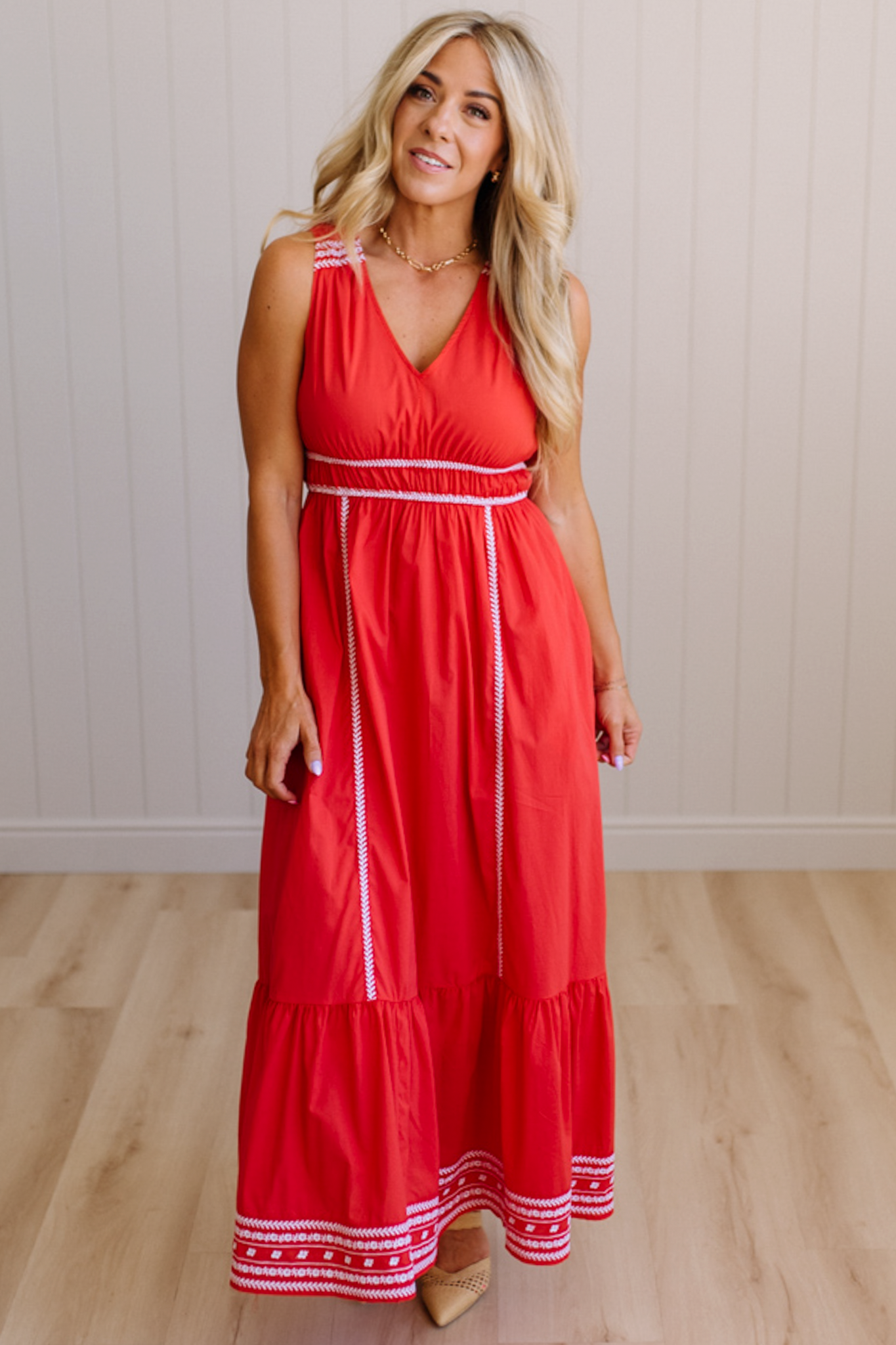 Woman wearing a red dress with white trim against a plain background
