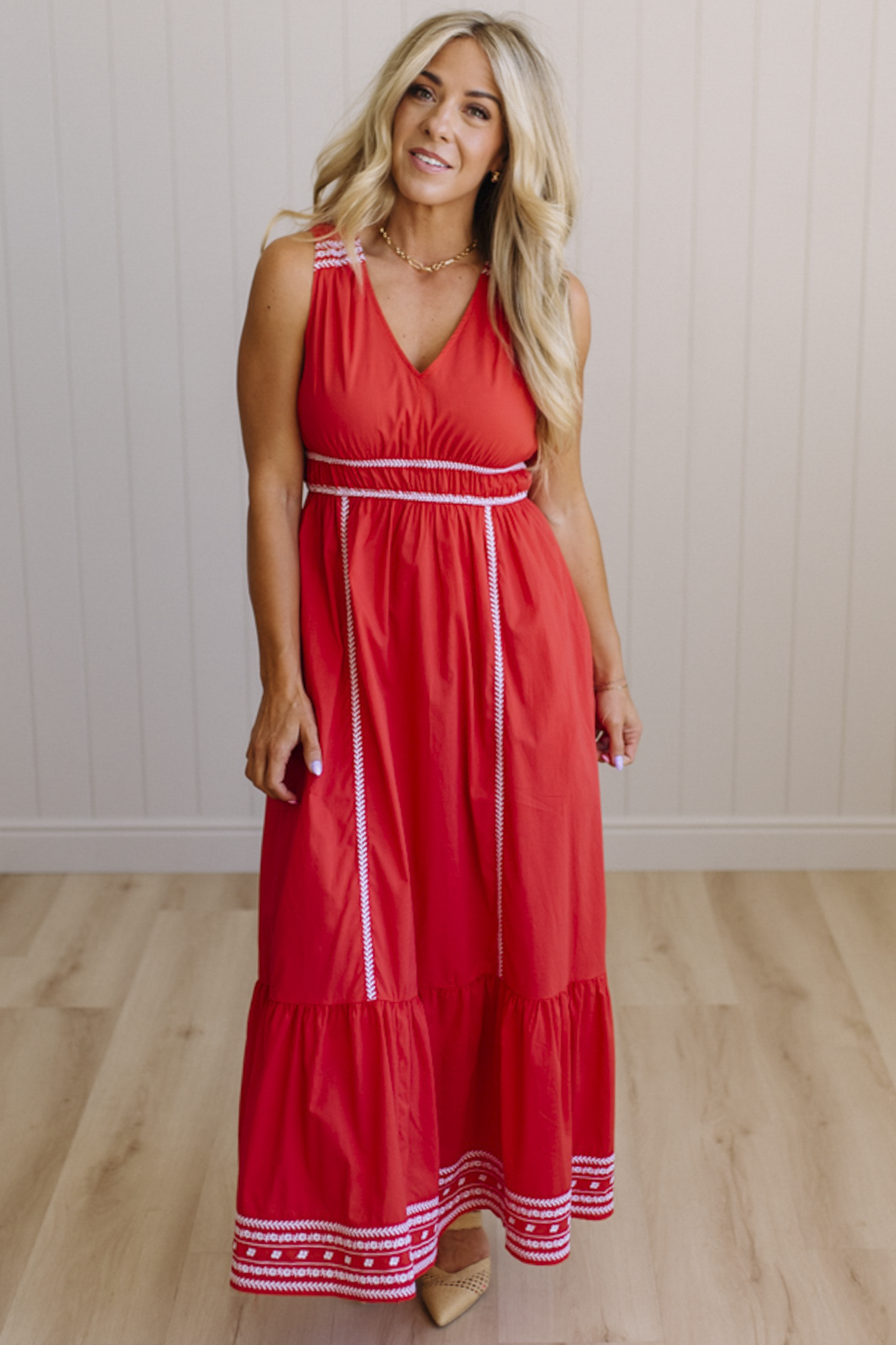 Woman wearing a red dress with white trim against a plain background