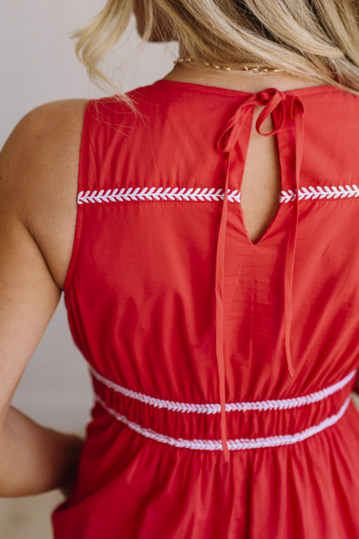 Red dress with white trim worn by a person, against a neutral background