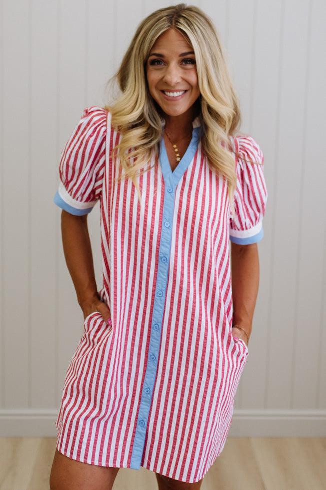 Woman wearing a red and white striped dress with blue trim against a neutral background