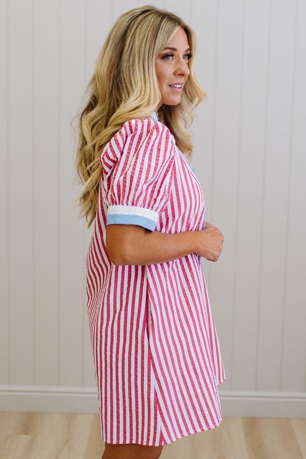 Woman wearing a red and white striped dress against a plain background