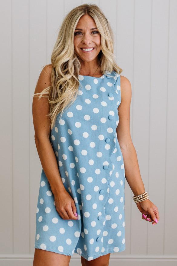 Woman wearing a blue dress with white polka dots against a light background
