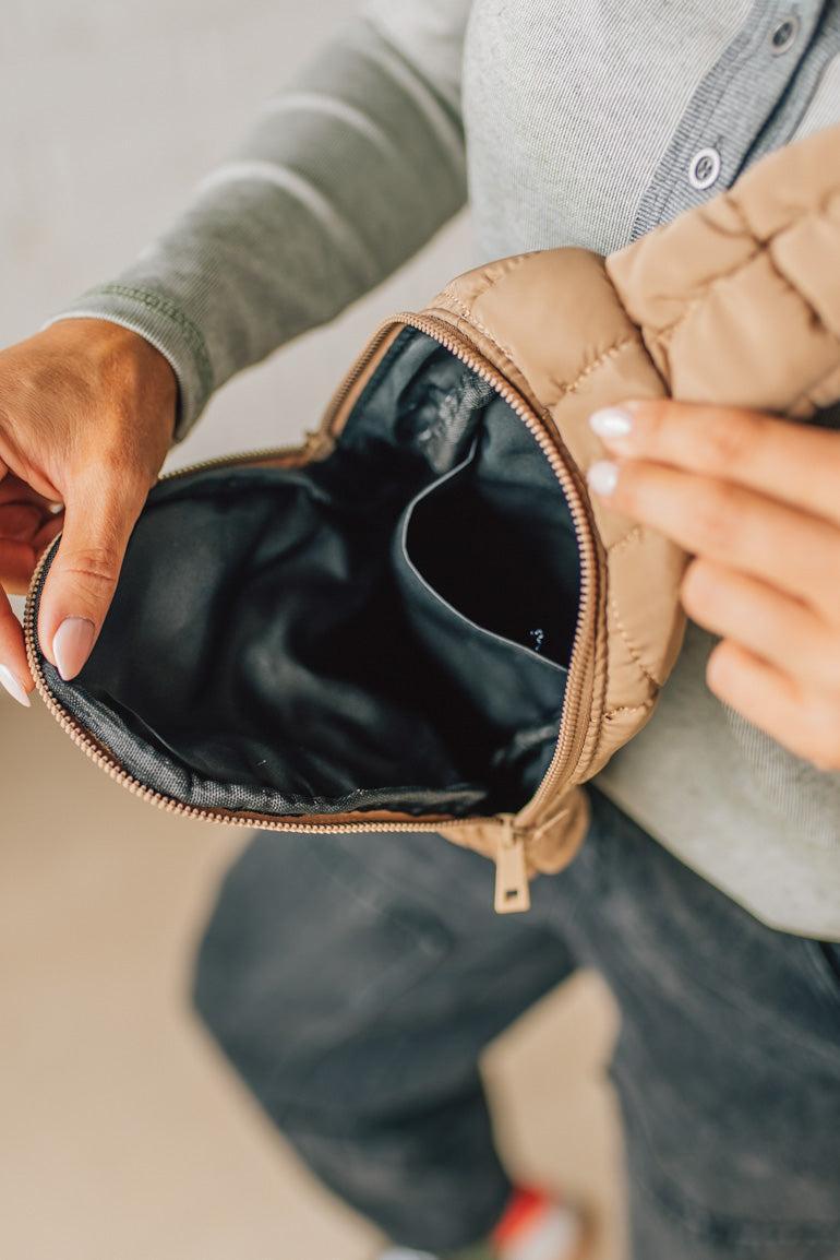 Person holding a beige pouch with a neutral background