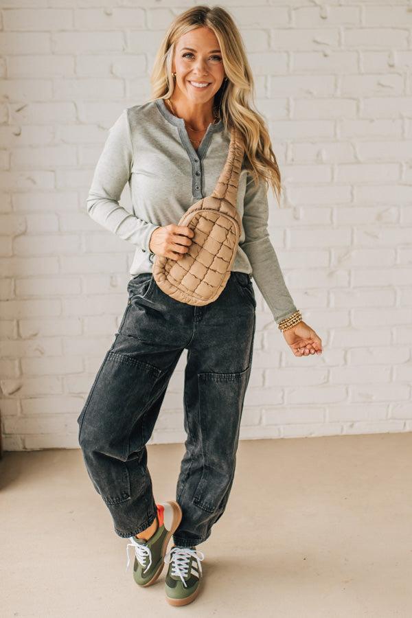 Woman holding a patterned bag against a white brick wall