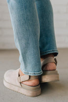 Women's beige sandals worn with blue jeans on a neutral background