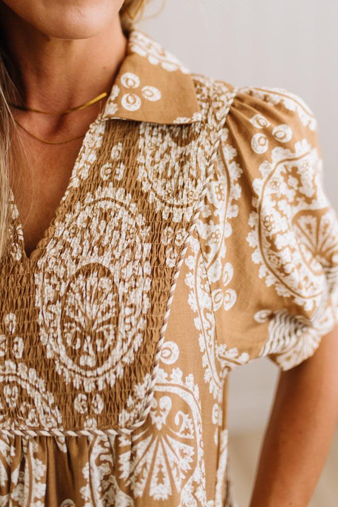 Close-up of a woman wearing a brown and white patterned blouse with puff sleeves and a smocked bodice.