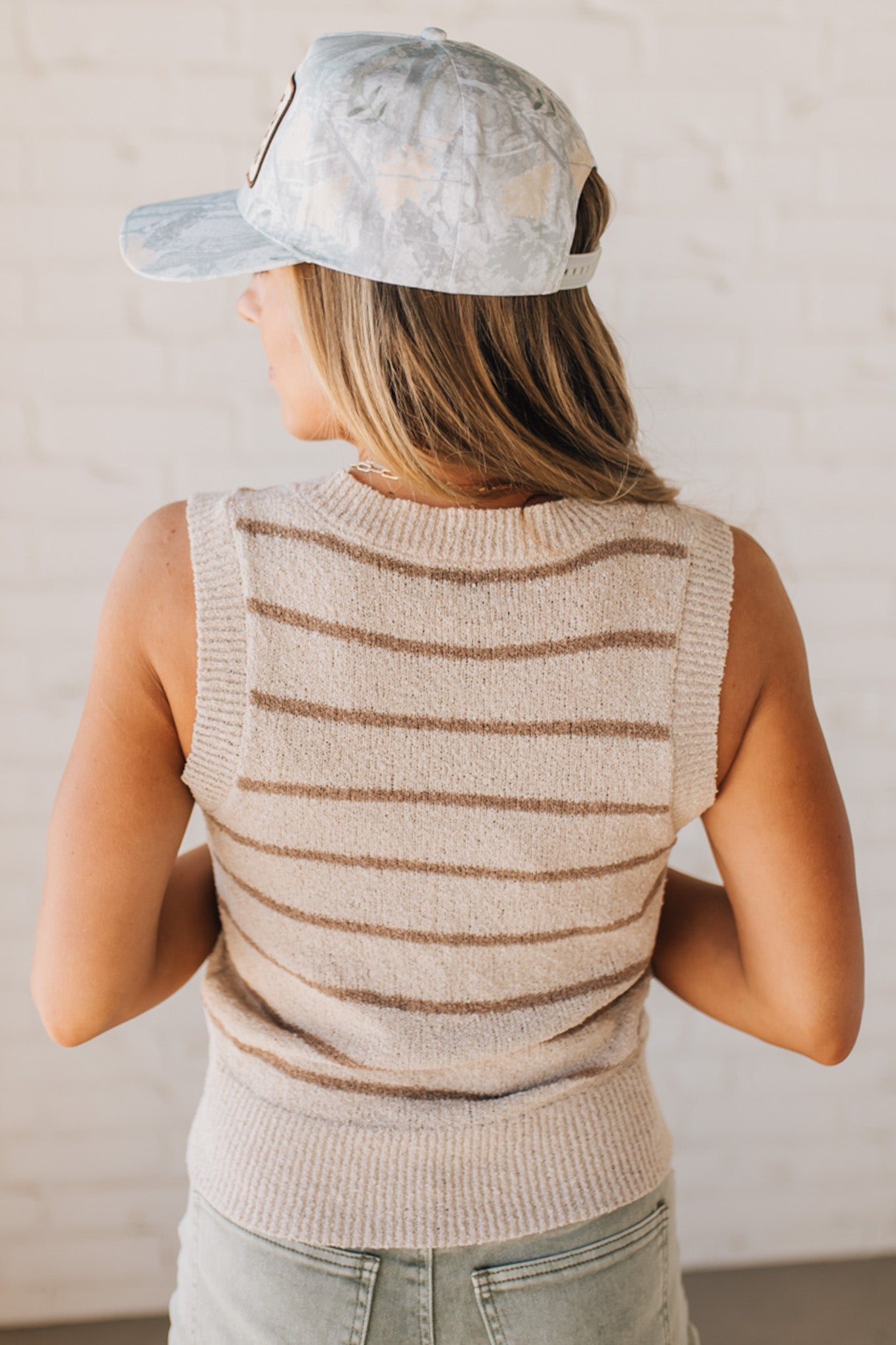 BLONDE WOMAN IN A HAT WEARING A LIGHTWEIGHT, COZY, STRIPED BUTTON UP V-NECK VEST W/ RIBBING ACCENTS THROUGHOUT BODY.