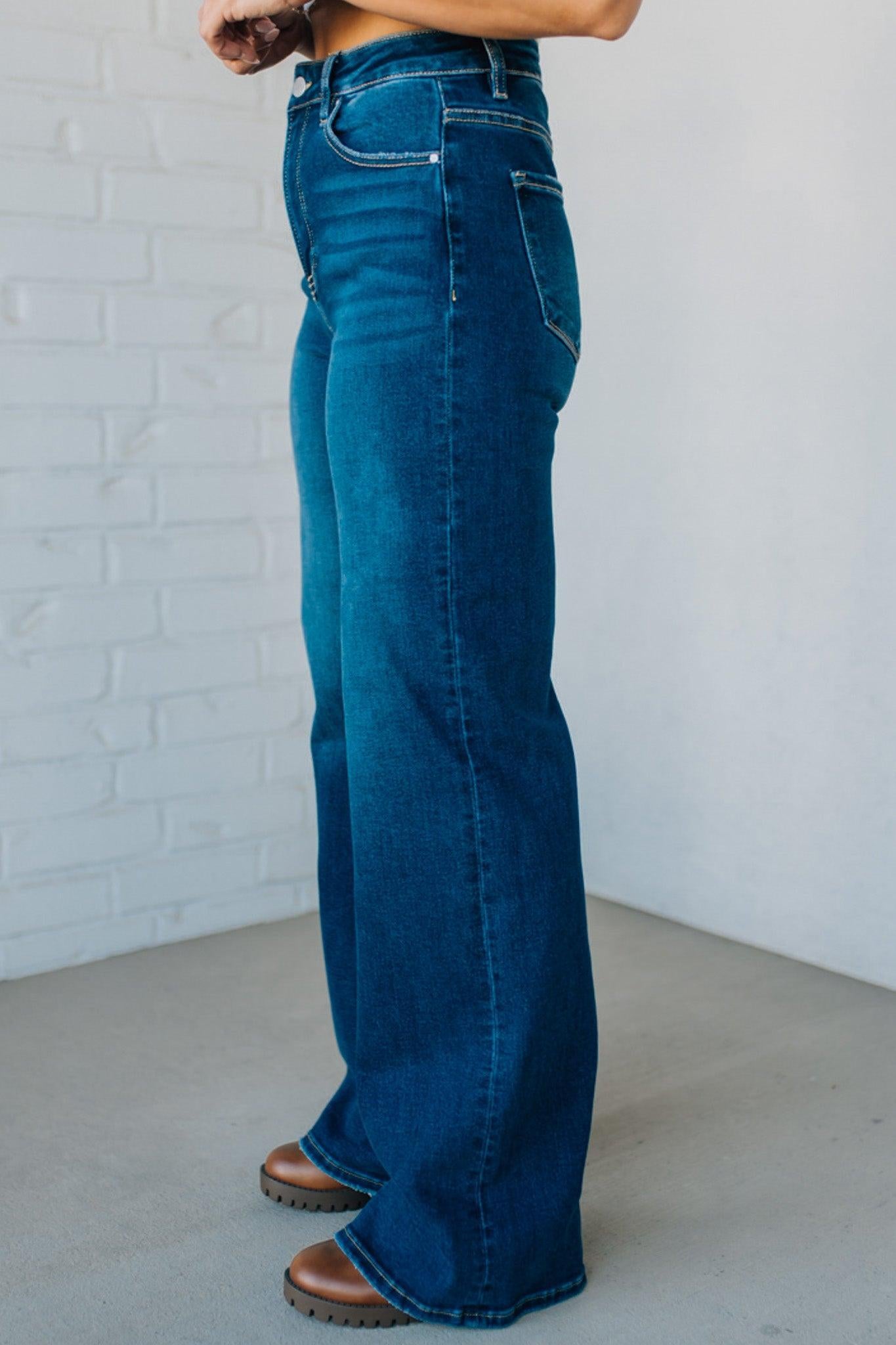 Person wearing blue jeans against a white brick wall.