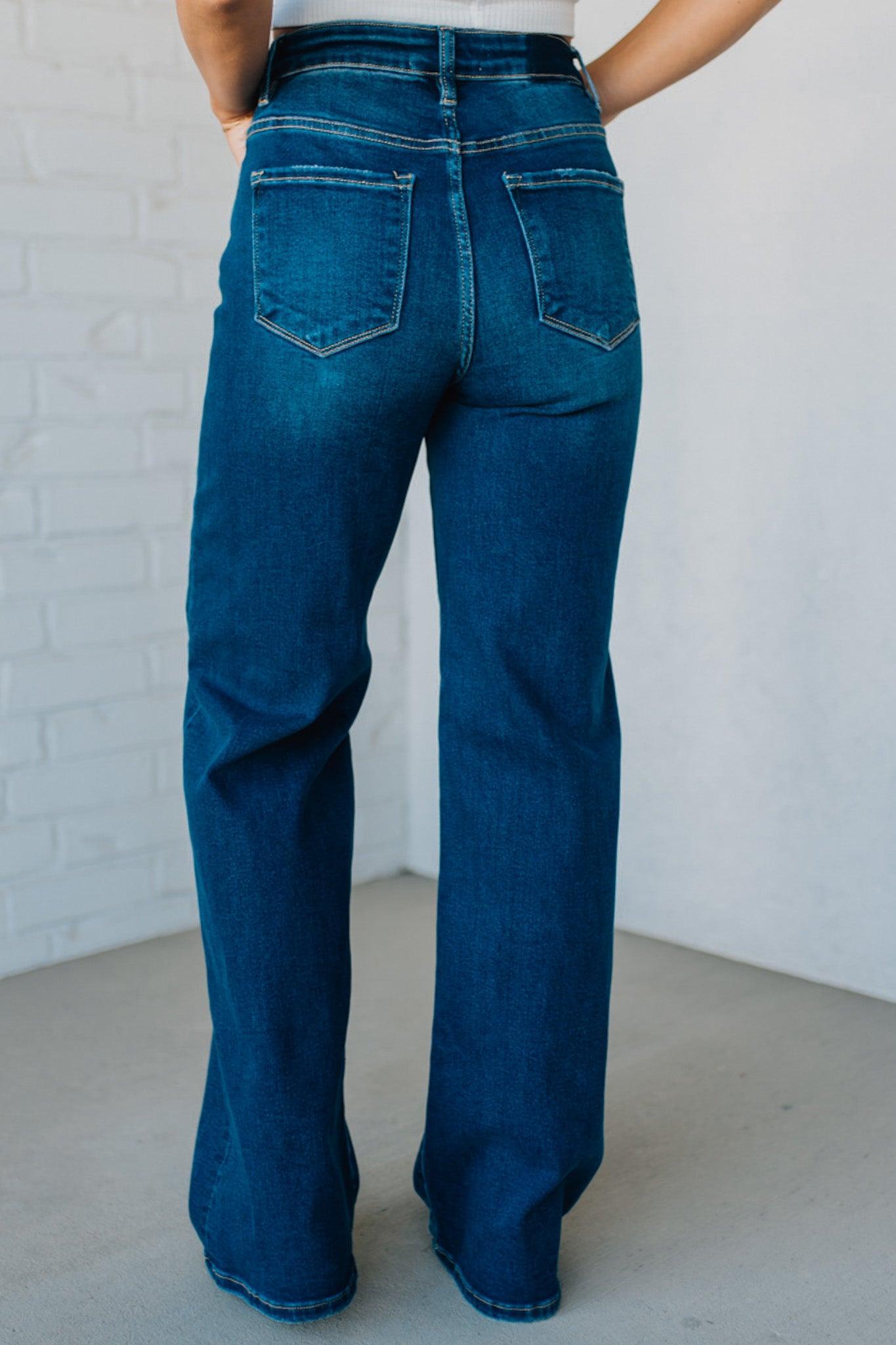 Person wearing blue jeans against a white brick wall.