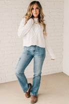 Blonde girl modeling a white long sleeve cable knit sweater