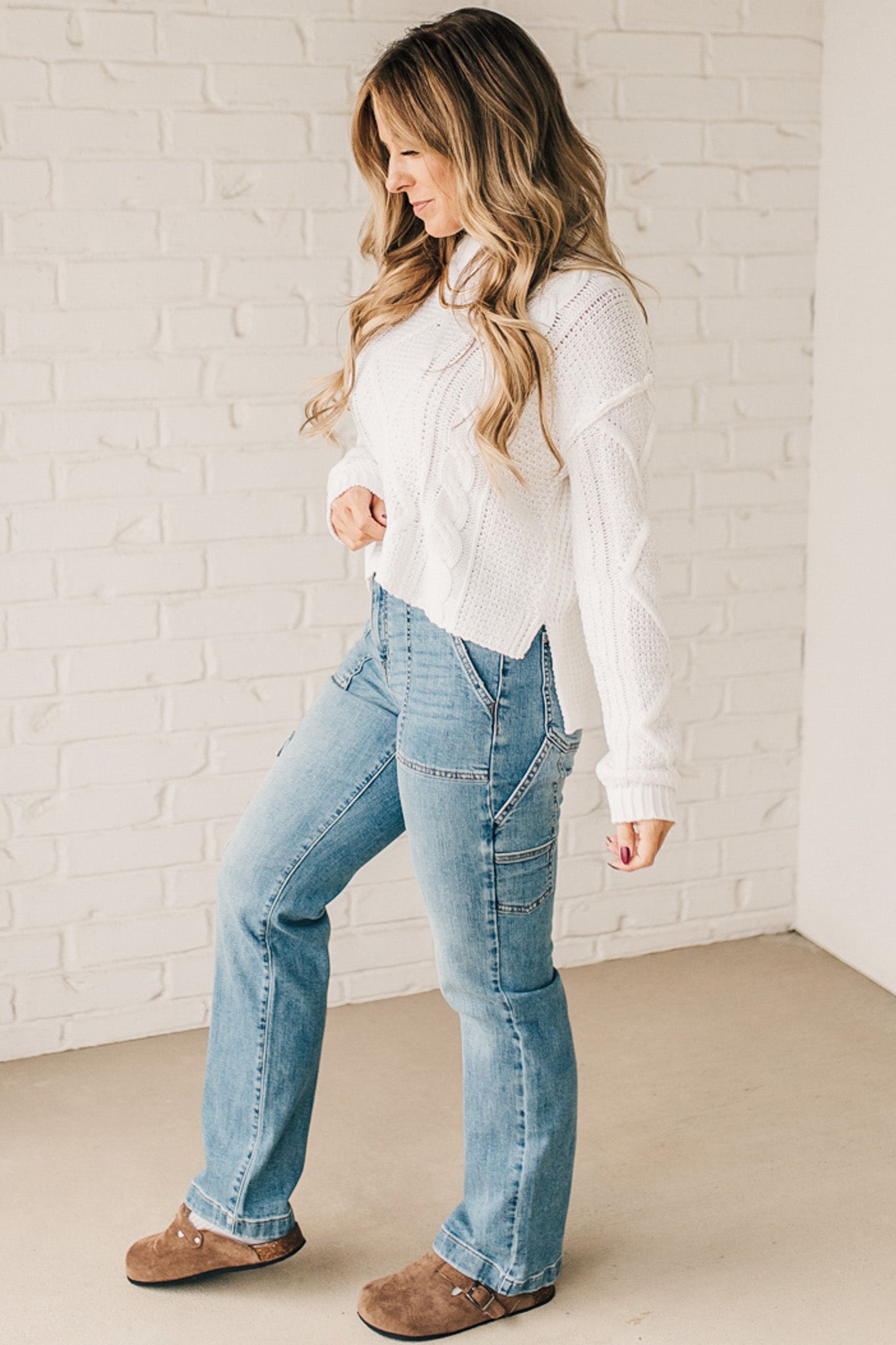 Blonde girl modeling a white long sleeve cable knit sweater