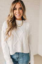 Blonde girl modeling a white long sleeve cable knit sweater