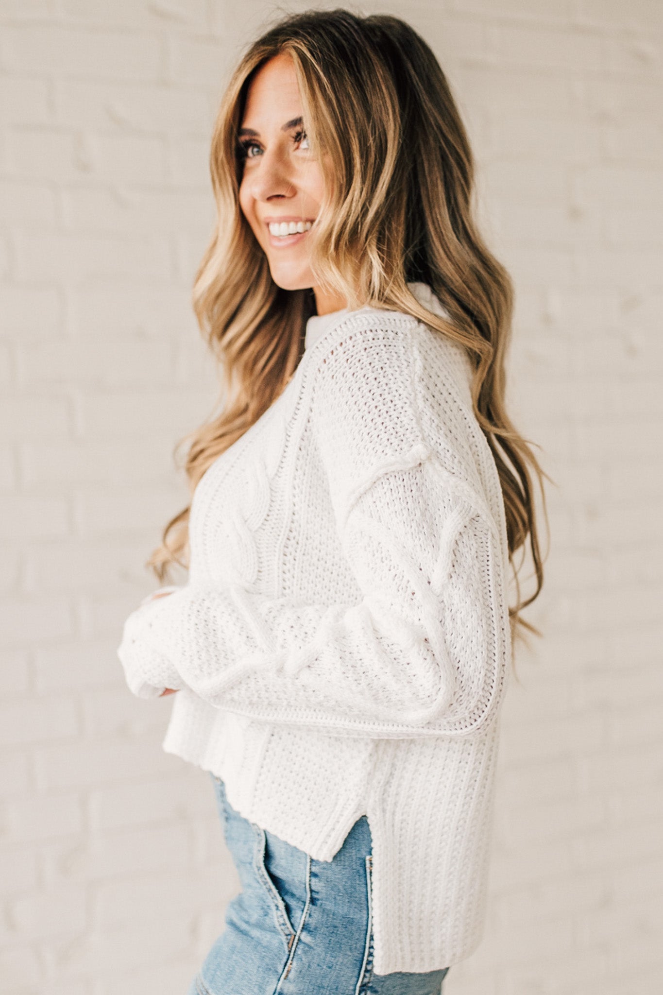 Blonde girl modeling a white long sleeve cable knit sweater