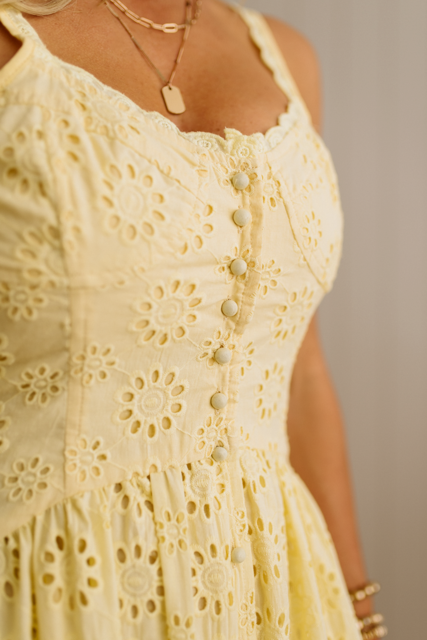 Blonde Woman wearing an eyelet lace dress with button front and spaghetti strap.