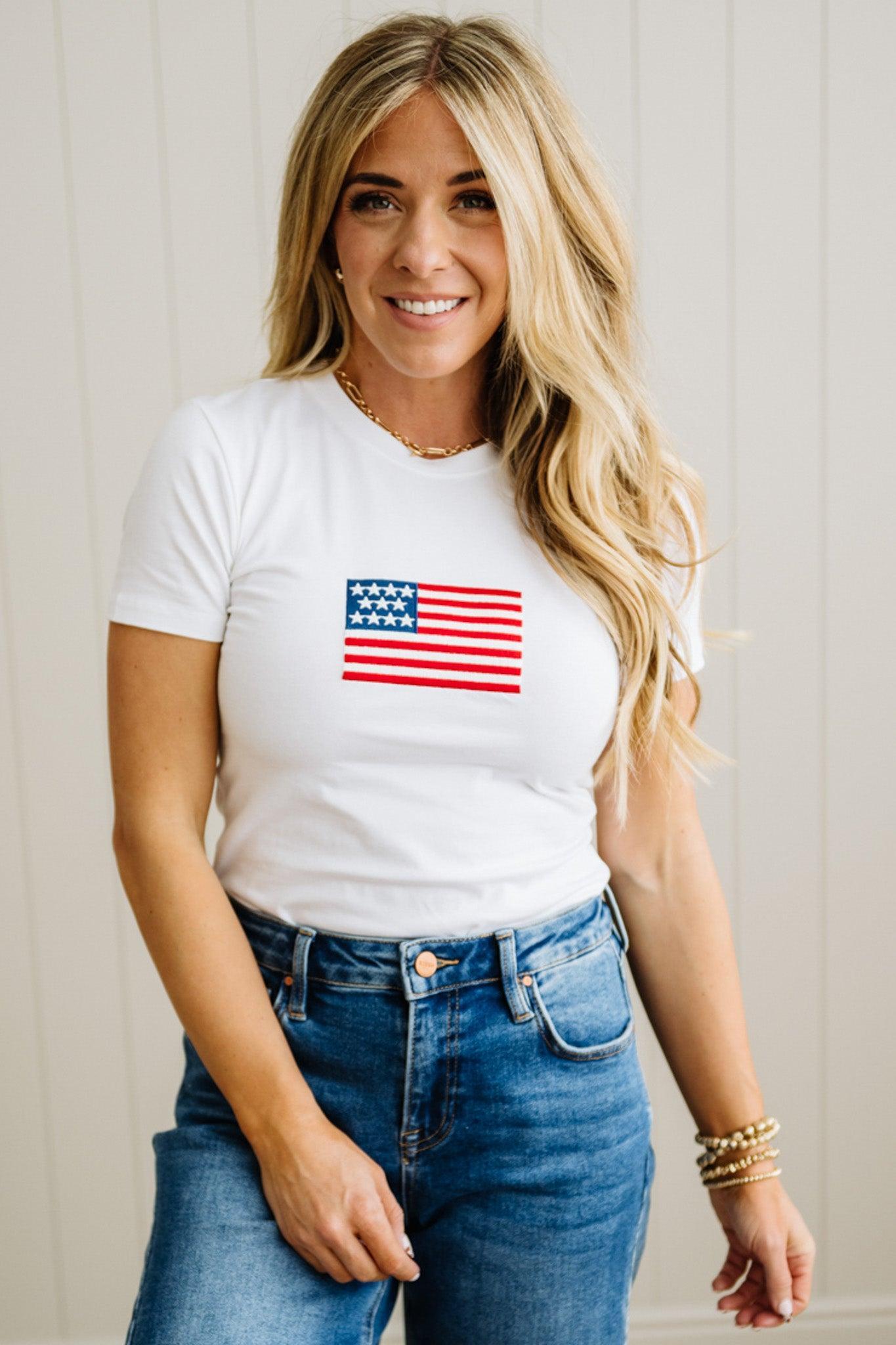Woman wearing a white t-shirt with an American flag design against a plain background