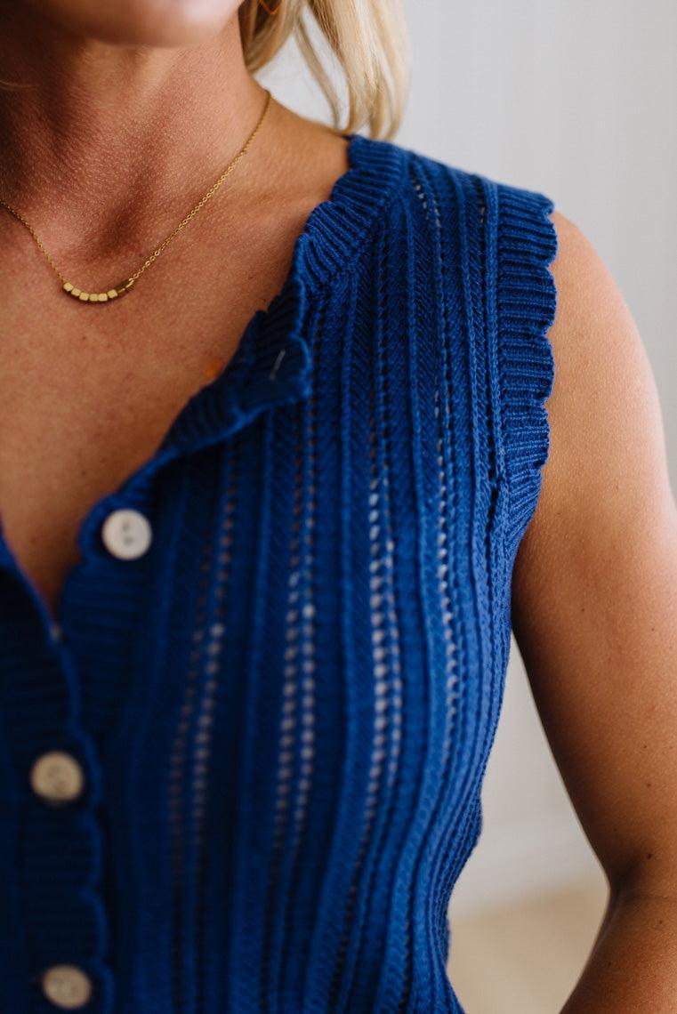 Close-up of a person wearing a blue ribbed sleeveless top with a blurred background
