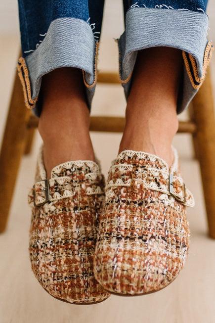 Womens footwear featuring a woven tweed upper with a statement buckle detail, set in an easy mule silhouette.