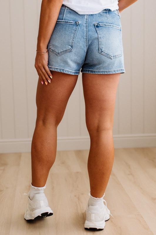 Person wearing light blue denim shorts on a wooden floor.