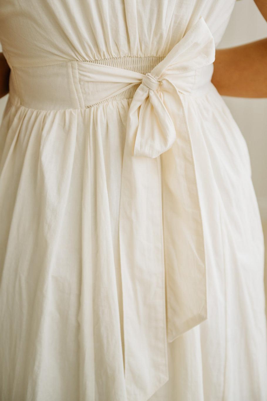 Close-up of a white dress with a bow detail on a blurred background