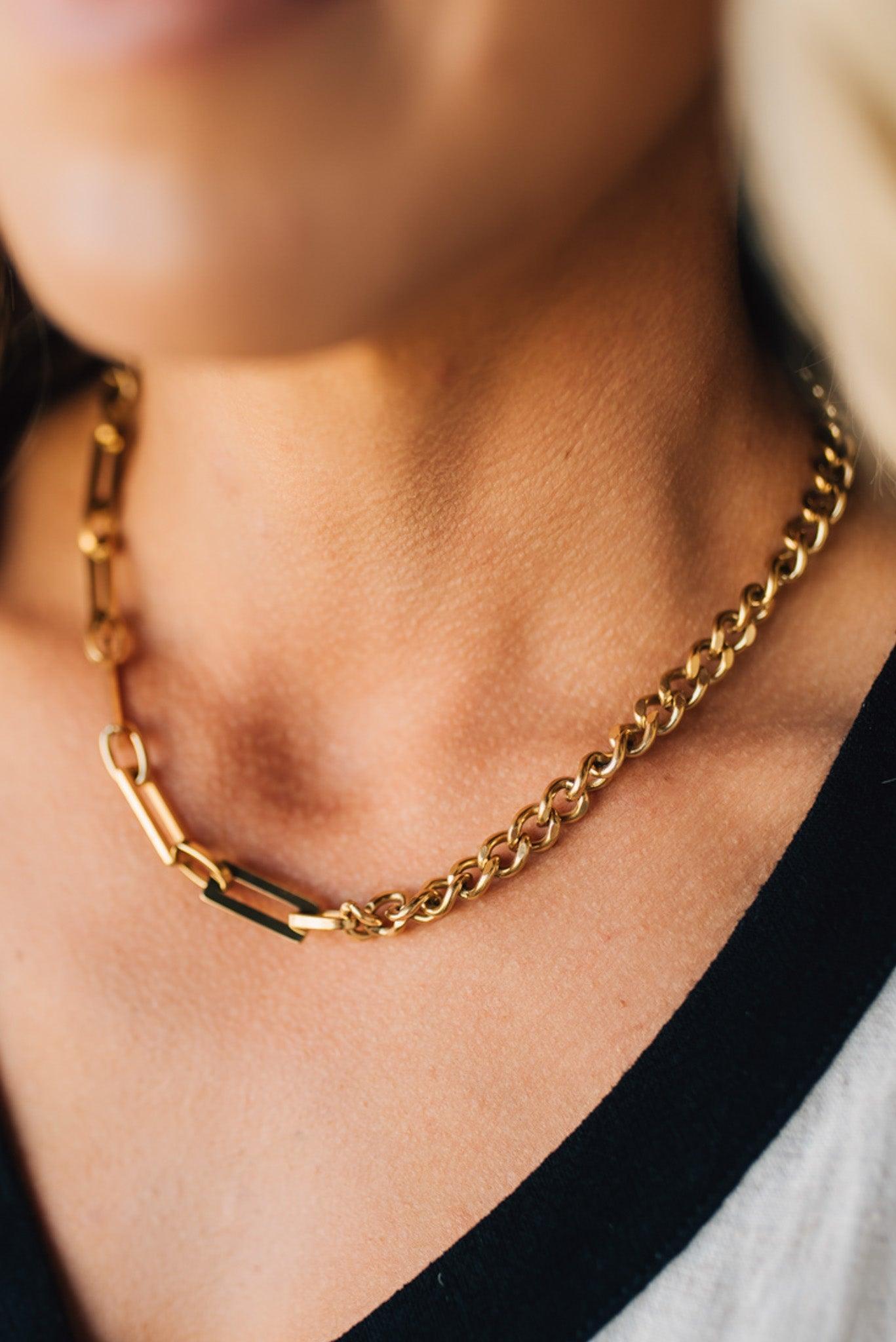 Gold chain necklace on a person wearing a black top.