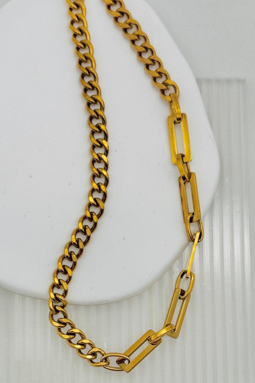 Gold chain necklace on a white stand with a white background
