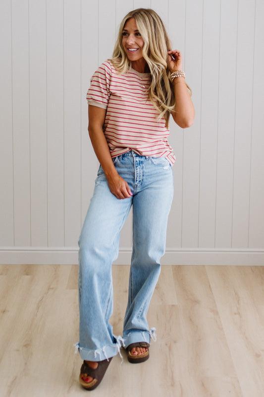 Woman wearing a red and white striped shirt and light blue jeans indoors.