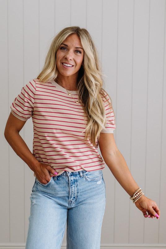 Woman wearing a striped shirt and jeans against a light background