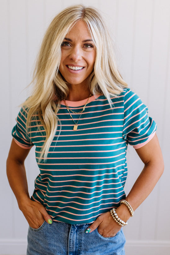 Woman wearing a green and white striped shirt with a plain background